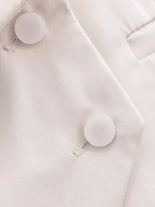 Gros plan sur la texture du tissu et les détails des boutons blancs d'un gilet beige