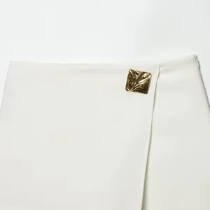 Elegant white asymmetrical skort featuring a unique textured gold metal square button