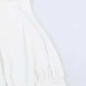Close-up of white pleated fabric detail on a fashionable halter neck dress.
