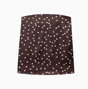 Détail d'un haut bandeau en satin marron foncé orné d'un motif classique à pois blancs élégant