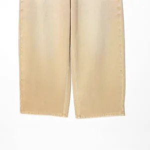 Gros plan d'une jambe de jean beige montrant la texture du tissu et les coutures de qualité