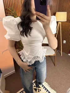 Close-up detail of a white puff sleeve top with delicate lace hem and slim fit design