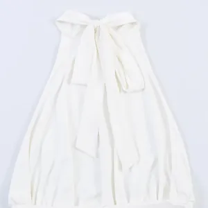 Close-up detail of a white pleated halter neck dress featuring an elegant large bow tie
