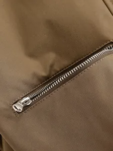 Macro detail shot showing a smooth silver metal zipper on a durable brown fabric vest