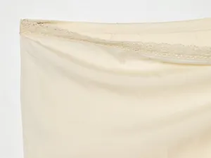 Close-up detail of delicate lace trim and smooth fabric on a cream midi skirt