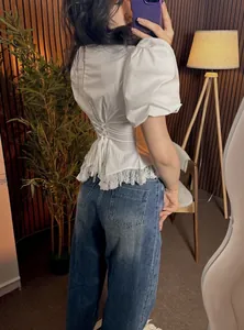 Detailed view of white puff sleeve top featuring corset back design and delicate lace trim.