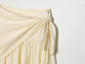 Close-up detail showing the elegant lace trim and side tie waist of a cream midi skirt