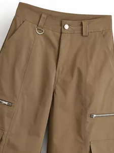 Close-up detail of stylish khaki cargo pants with zipper pockets and metal D-ring belt loop
