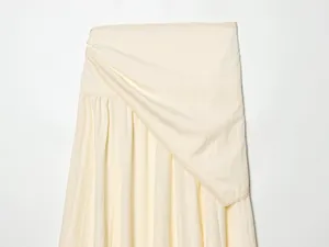 Detailed view of the elegant lace trim and draped asymmetrical overlay on the midi skirt