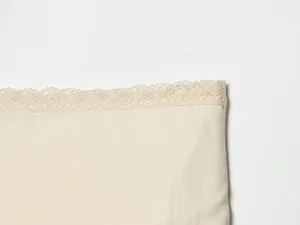 Detailed macro view of the delicate lace trim hem on an off-white fashion midi skirt