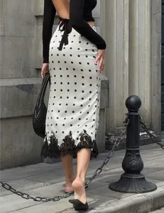 Detailed back view of white polka dot midi skirt featuring a black lace trim hemline