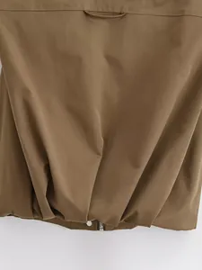 Close-up of brown cargo vest hem featuring zipper detail and sturdy woven fabric