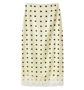 Detailed macro view of a cream midi skirt featuring black polka dots and white lace hem trim