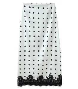 Detailed view of the black lace hem and polka dot pattern on a white midi skirt