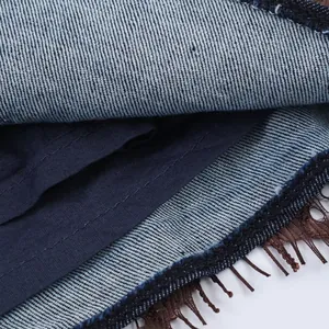 Macro del tessuto denim e del bordo in pizzo marrone di una gonna pantalone alla moda