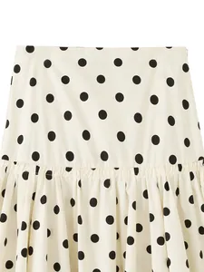 Close-up detail of the white fabric with black polka dots and pleated hem design.