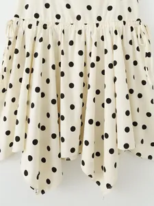 Close-up of a cream-colored polka dot asymmetric mini skirt showing fabric detail