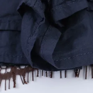 Dettaglio ravvicinato dell'orlo dello skort in denim blu navy con pizzo marrone.