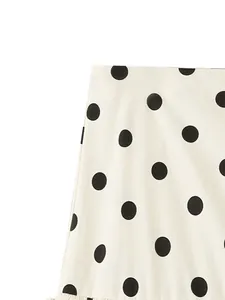 Close-up detail of white mini skirt featuring a classic large black polka dot print.