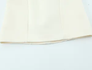Detailed close-up view showing the hemline stitching on creamy white mini dress fabric