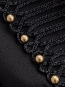 Macro detail of elegant military style braided cord and bronze buttons on black blazer