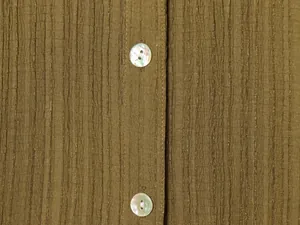 Macro view of textured olive green shirt fabric featuring iridescent pearlescent buttons