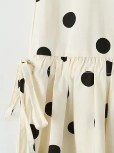 Detailed macro view of white polka dot mini skirt featuring ruffle waist and drawstring side tie