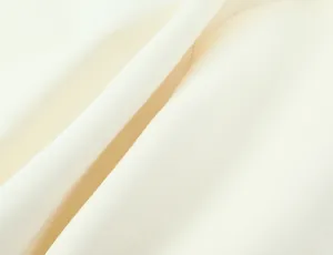 Detailed macro shot of the smooth cream fabric texture for the fluffy mini dress