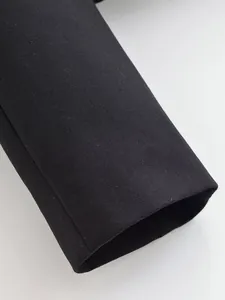 Close-up macro view of the sleeve cuff on a high-quality black slim fit blazer garment.