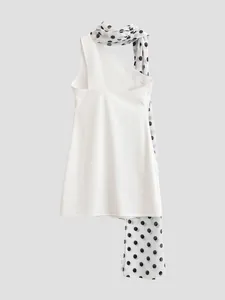 Close-up detail view of a white dress featuring a stylish black polka dot scarf neck tie.