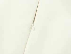 Macro close-up showing the hidden zipper detail on a stylish white puff mini dress.