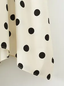 Macro view showing the detailed texture and black polka dot print of the white skirt