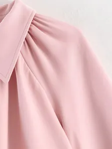 Vue détaillée du revers rose et de la couture de l'épaule plissée sur le blouson.