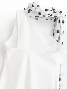 Detail of white dress featuring asymmetrical neckline with black polka dot scarf accent