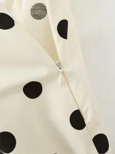 Detailed close-up showing the white invisible zipper on a cream polka dot mini skirt
