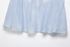 Macro detail of a light blue crinkled fabric garment with elegant white lace trim detail