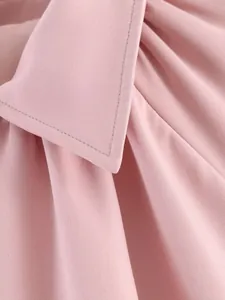 Gros plan sur la texture du tissu et les coutures d'une veste bomber rose à revers.