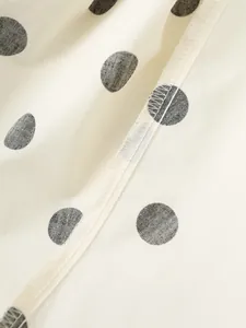 Detailed macro view of the internal seam and black polka dot pattern on cream fabric