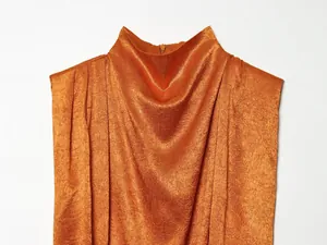 Detail van een oranje zijden satijnen top met gedrapeerde halslijn en geplooide schouders