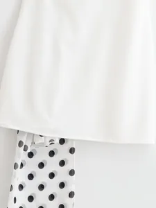 Close-up detail of a minimalist white dress featuring a stylish black polka dot scarf accent