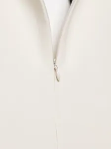 Nahaufnahme eines haltbaren verdeckten Reißverschlusses an einem cremefarbenen Kleid.