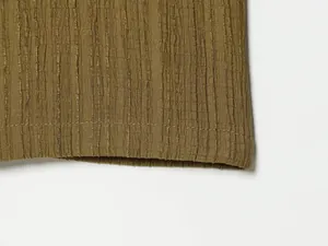 Close-up detail of vertical crinkle fabric texture and hemline on olive green shirt set