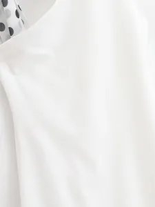 Detailed close-up view of a white halter dress featuring a polka dot scarf accent