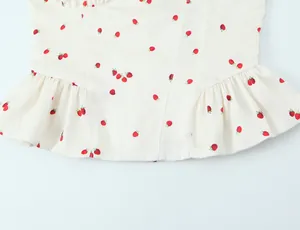 Detail view of strawberry print satin top showing ruffle hem and smooth fabric texture.