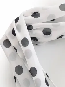 Close-up detail of lightweight white chiffon fabric with black polka dots