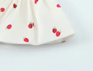Detailed close-up of white satin fabric with vibrant strawberry print and hem stitching.