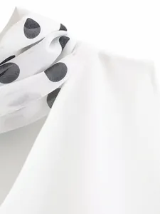 Detail view of the white halter neck dress with a polka dot scarf accessory.