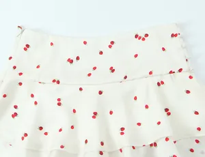 Macro view of strawberry print tiered mini skirt featuring satin texture and side buttons