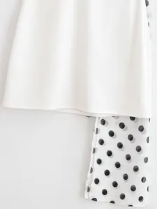 Detailed close-up showing the elegant white fabric and black polka dot scarf accent of this dress