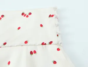 Close-up of strawberry print fabric and white buttons on a cream satin garment